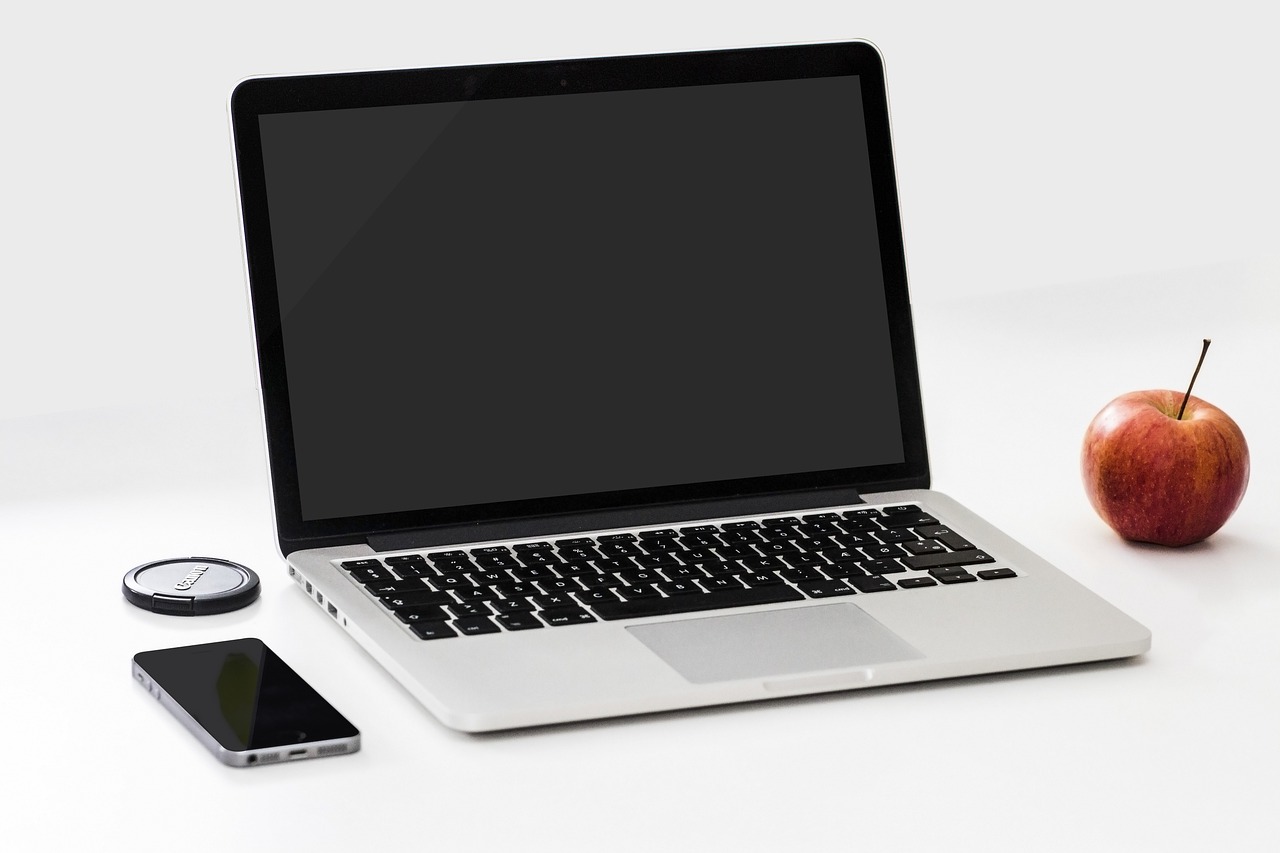 Arbeitsplatz mit Laptop, Smartphone und Apfel – Symbolbild für digitales betriebliches Gesundheitsmanagement in Leipzig.