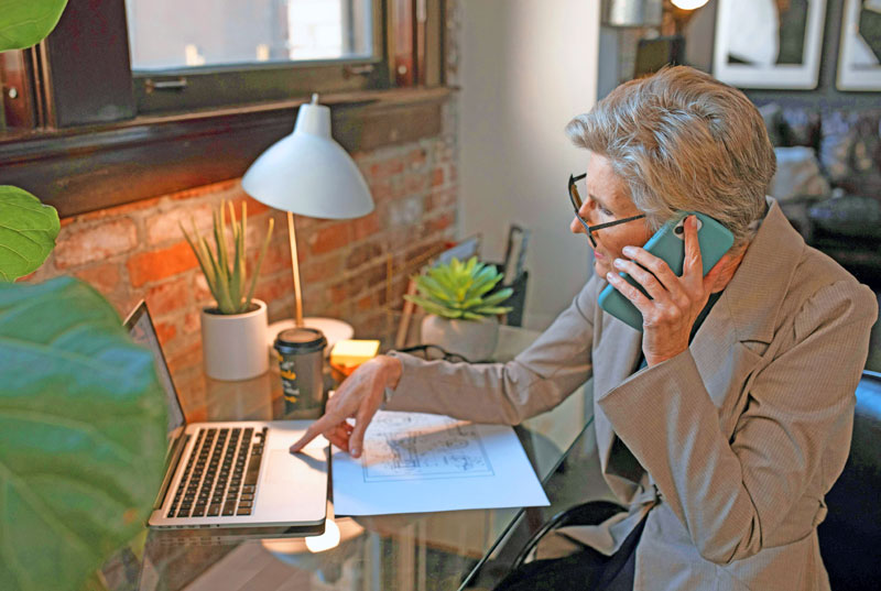 Ältere Frau arbeitet am Laptop und telefoniert im Homeoffice – Symbolbild für Aktivrente 2026 in Leipzig und flexible Arbeit im Ruhestand.