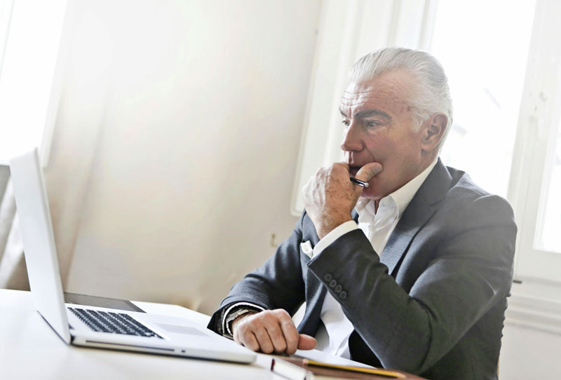 Älterer Mann im Anzug arbeitet konzentriert am Laptop – Symbolbild für Aktivrente und berufliche Tätigkeit im Ruhestand.