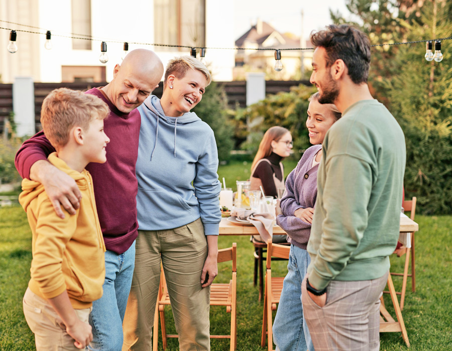 Mehrgenerationen-Familie und Freunde lachen im Garten zusammen – Symbol für gemeinsame Altersvorsorge und Lebensplanung.