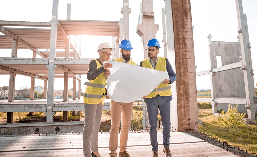 Drei Bauingenieure mit Helm und Bauplan auf Baustelle – Berufsunfähigkeitsversicherung für Bauwesen in Leipzig