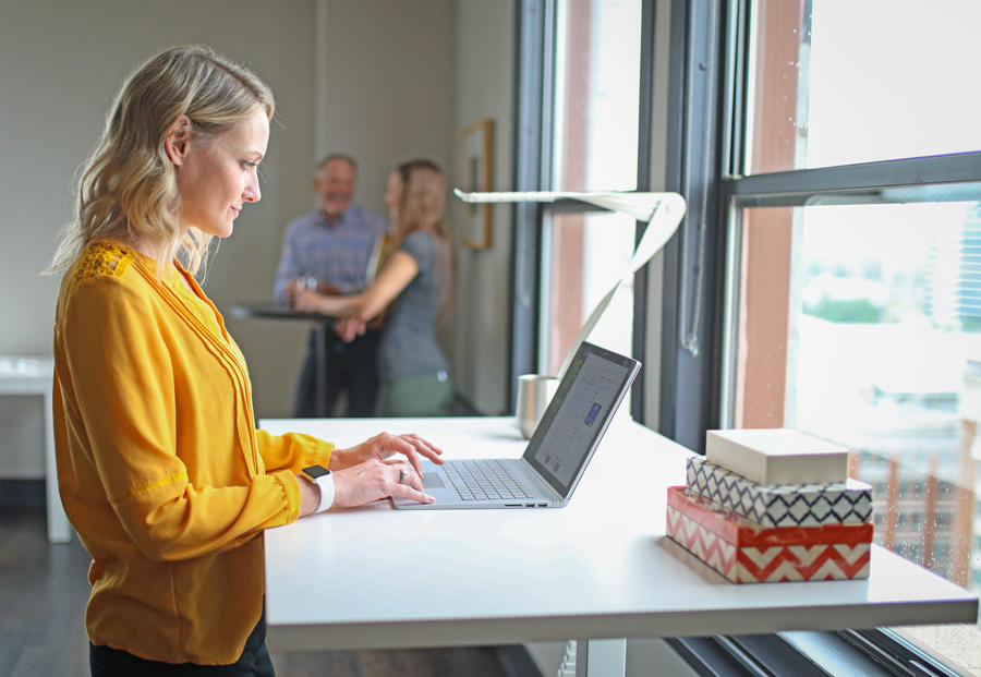 Frau arbeitet im Stehen an einem Laptop – BU-Versicherung für Homeoffice und Bürojobs in Leipzig