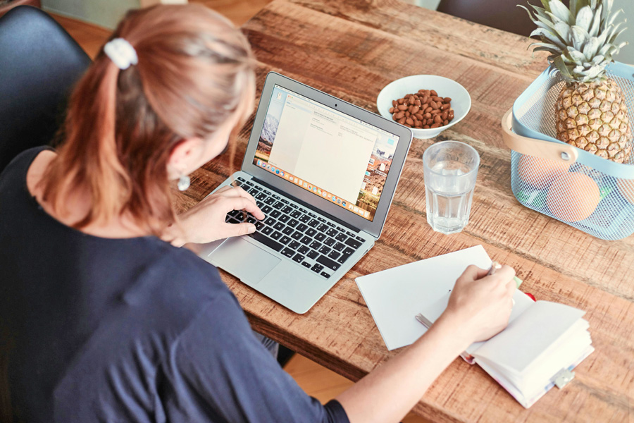 Eine Person arbeitet konzentriert am Laptop und Notizblock, um online eine Haftpflichtversicherung abschließen zu können, in produktiver Arbeitsatmosphäre.