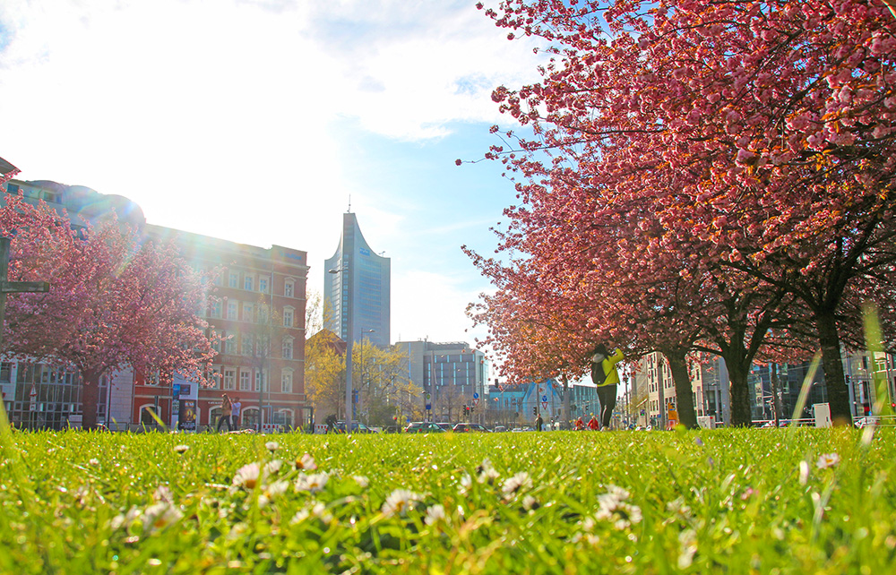 Stadtbild von Leipzig im Frühling mit Wohnhäusern und dem City-Hochhaus – perfekte Lage für Immobilieninvestitionen und Altersvorsorge