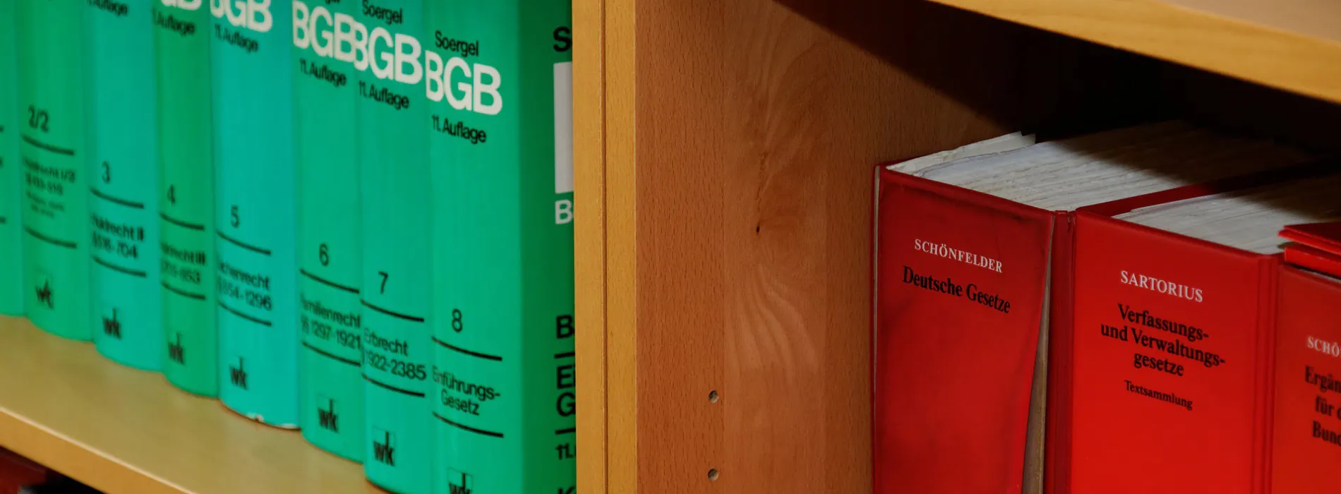 Nahaufnahme eines Regals mit rechtlichen Fachbüchern. Auf der linken Seite sind grüne Bände des BGB (Bürgerliches Gesetzbuch) aus der Reihe "Soergel" zu sehen, nummeriert von Band 2 bis Band 8. Auf der rechten Seite befinden sich rote Bände mit der Aufschrift "Schönfelder - Deutsche Gesetze" und "Sartorius - Verfassungs- und Verwaltungsgesetze". Die Darstellung unterstreicht die Bedeutung einer umfassenden Rechtsschutzversicherung, wie sie von Finanzkompass Leipzig angeboten wird.