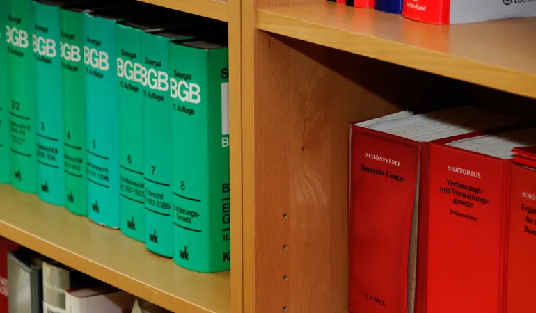 Nahaufnahme eines Regals mit rechtlichen Fachbüchern. Auf der linken Seite sind grüne Bände des BGB (Bürgerliches Gesetzbuch) aus der Reihe "Soergel" zu sehen, nummeriert von Band 2 bis Band 8. Auf der rechten Seite befinden sich rote Bände mit der Aufschrift "Schönfelder - Deutsche Gesetze" und "Sartorius - Verfassungs- und Verwaltungsgesetze". Die Darstellung unterstreicht die Bedeutung einer umfassenden Rechtsschutzversicherung, wie sie von Finanzkompass Leipzig angeboten wird.