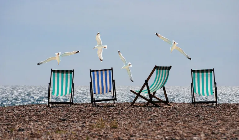 Verlassene Liegestühle am leeren Strand bei Sonnenschein – Symbolbild für entgangenen Urlaub und Anspruch auf Schadenersatz