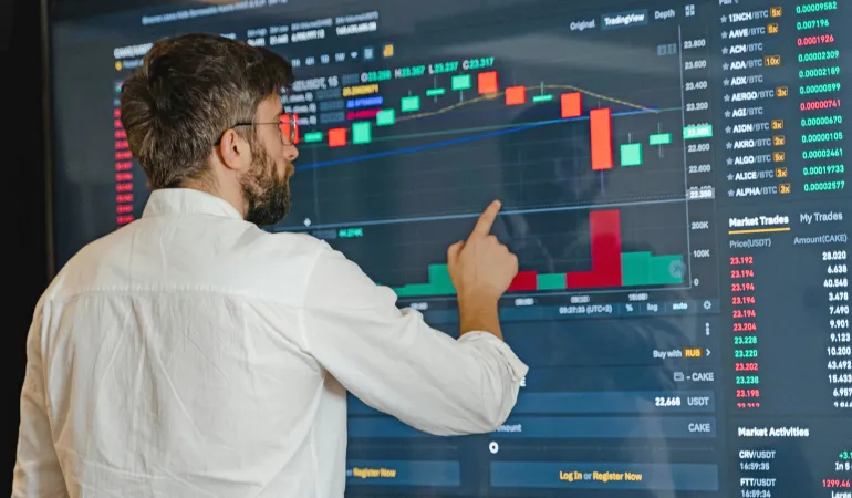 Mann analysiert Kursdiagramme auf einem großen Bildschirm als Symbol für digitales Geld anlegen an der Börse