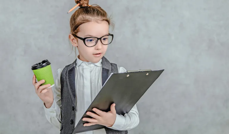 Ein junges Mädchen in Business-Kleidung mit Brille hält einen Klemmbrett-Ordner und einen Kaffeebecher in der Hand. Ihr Haar ist mit zwei Stiften hochgesteckt. Das humorvolle Bild symbolisiert den Einstieg ins Berufsleben und zeigt auf spielerische Weise die Bedeutung von Versicherungen für Berufseinsteiger.