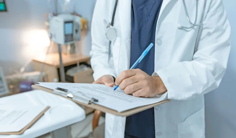 Mediziner dokumentiert Untersuchungsergebnisse auf einem Formular – typisches Szenario bei gesundheitlichen Einschränkungen, die zur Berufsunfähigkeit führen können. In Leipzig ist eine passende Berufsunfähigkeitsversicherung wichtig, um finanzielle Risiken frühzeitig abzusichern.