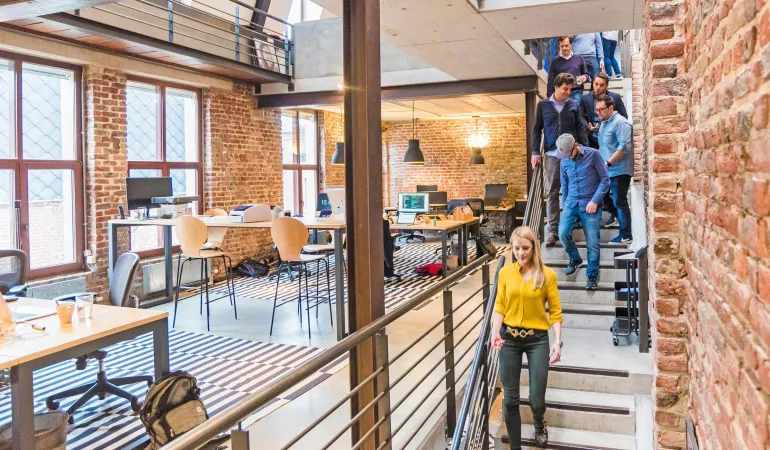Angestellte verlassen ein modernes Bürogebäude mit Backsteinwänden und offener Arbeitsatmosphäre – Symbolbild für Betriebliche Altersvorsorge in zukunftsorientierten Unternehmen