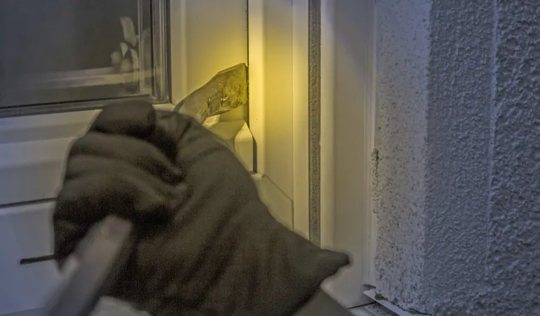 Einbruch in ein Fenster mit Brecheisen bei Nacht – Hausratversicherung Leipzig schützt vor Einbruch