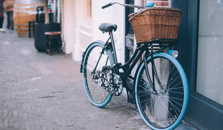 Schwarzes Fahrrad mit blauem Reifen und Korb vor Hauswand – perfekte Absicherung durch Fahrrad Versicherung in Leipzig
