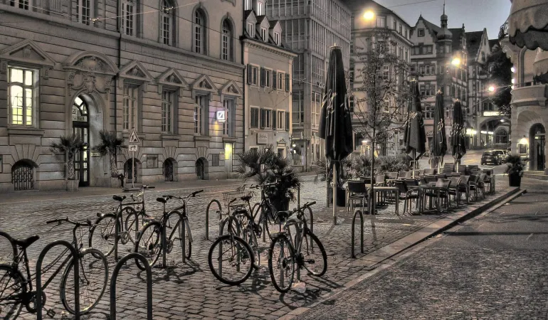 Fahrradständer mit mehreren Fahrrädern im abendlichen Stadtzentrum – optimale Absicherung durch Fahrradversicherung in Leipzig