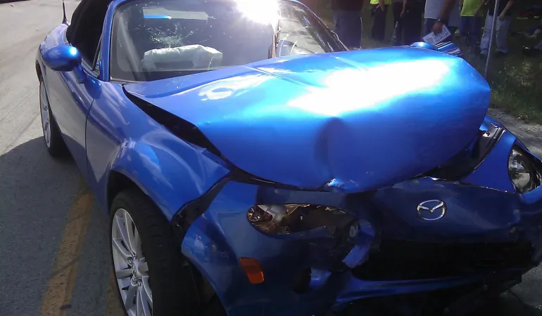  Blauer Mazda mit starkem Frontschaden nach einem Unfall – Symbolbild für günstige Autoversicherung in Leipzig.