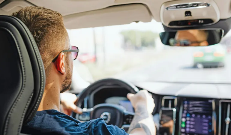 Rückansicht eines Autofahrers am Steuer in einem modernen Fahrzeug – Symbolbild: Kfz-Versicherung nach Unfall wechseln