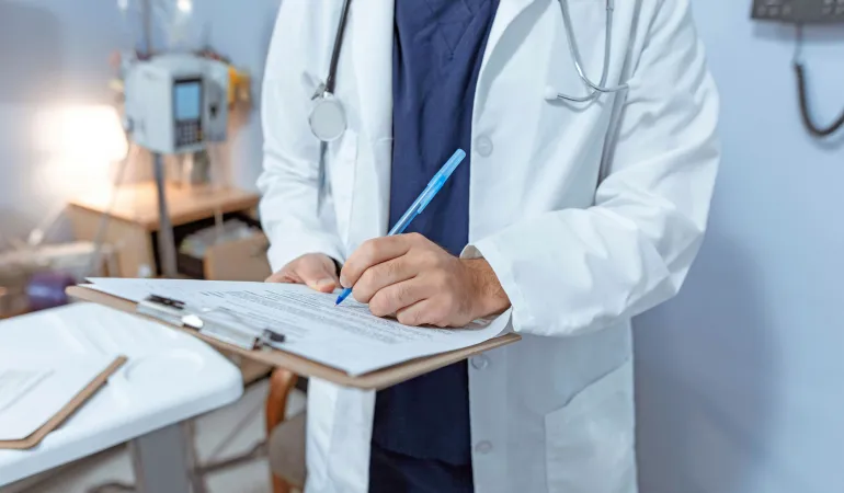 Arzt füllt Formular aus – Krankenkassenbeiträge 2026 steigen: Beratung zur Krankenkasse und Zusatzbeitrag