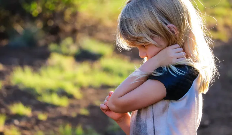 Nachdenkliches blondes Mädchen im Freien bei Sonnenlicht – Symbolbild für die Bedeutung einer privaten Unfallversicherung für Kinder in Leipzig.