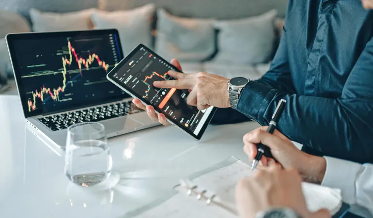 Finanzberater zeigt auf Tablet und Laptop Kursverläufe und Börsengrafiken zur Erklärung von ETF-Sparplan und Vermögensaufbau in Leipzig